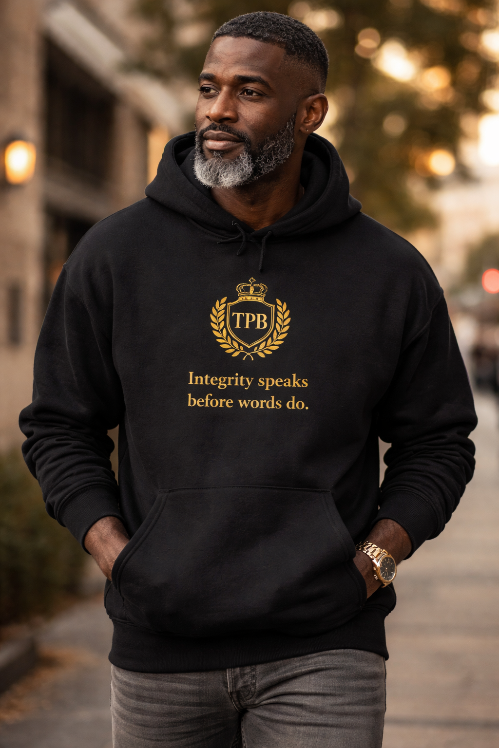 Urban lifestyle photo of Black man wearing navy hoodie with gold integrity statement